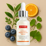 Gymsegbe Luminous Mighty Punch Serum bottle with blueberries, oranges, and leaves on a beige background