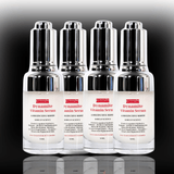 Four bottles of Dynamite Vitamin Serum on a reflective surface with a dark background