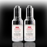 Two bottles of Dynamite Vitamin Serum on a reflective surface with a gradient background