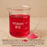 Beaker of red liquid labeled 'Vitamin B12' with a bowl of pink powder on a beige background.