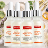 Four bottles of Gymsegbe Luminous Mighty Punch Serum on a natural background with herbs and fruits.