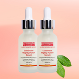 Two bottles of gymsegbe atlante Luminous Mighty Punch Serum on a pink background with green leaves.