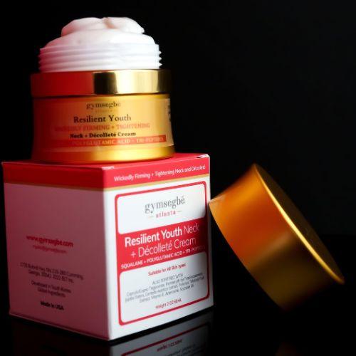 opened jar of neck cream on a neck cream box showing cream on a bblack background